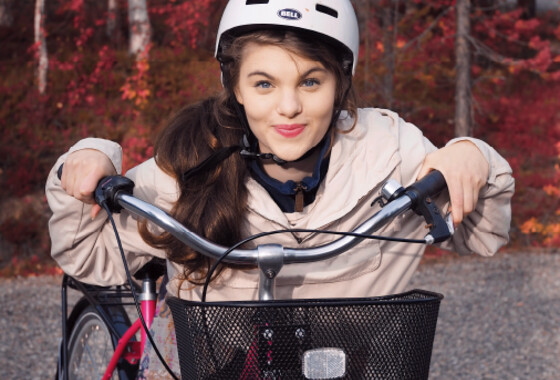 nainen kypärä päässä nojaa polkupyörään.