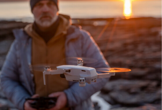 mies lennättää dronea ilta-auringossa.