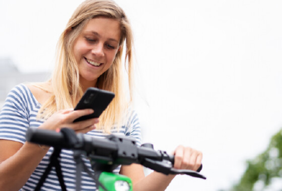 Polkupyörään nojaava nainen katsoo kännykkäänsä