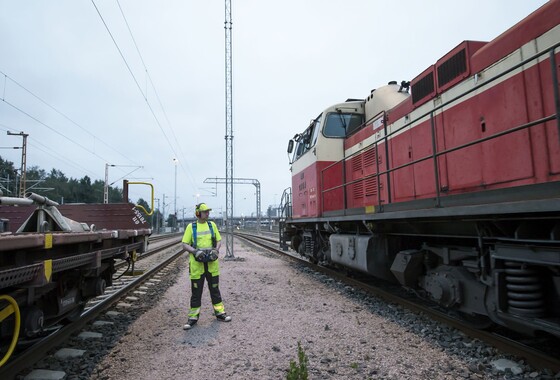 Kuvassa vaihtotyönjohtaja seisoo ratapihalla veturin vieressä ohjaa veturia radio-ohjauksella.