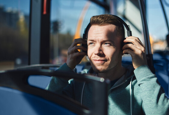 mies kuulokkeet korvilla bussissa