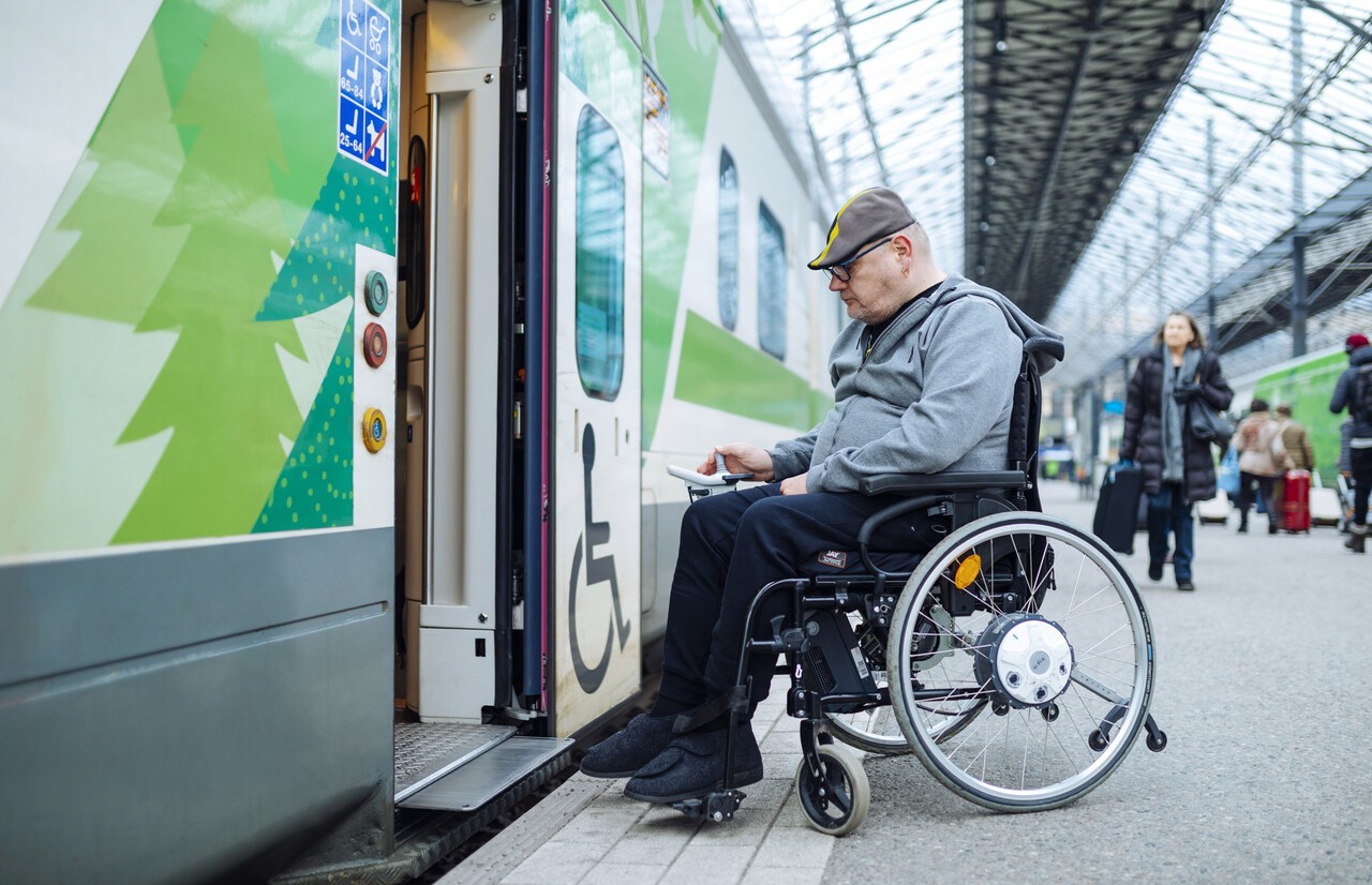 Pyörätuolissa istuva mies nousemassa junaan Helsingissä. 