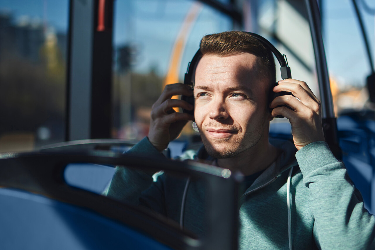 mies kuulokkeet korvilla bussissa